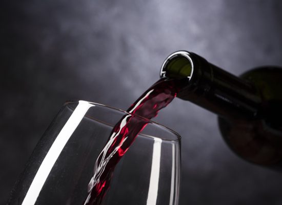 pouring red wine into a glass with a dark background